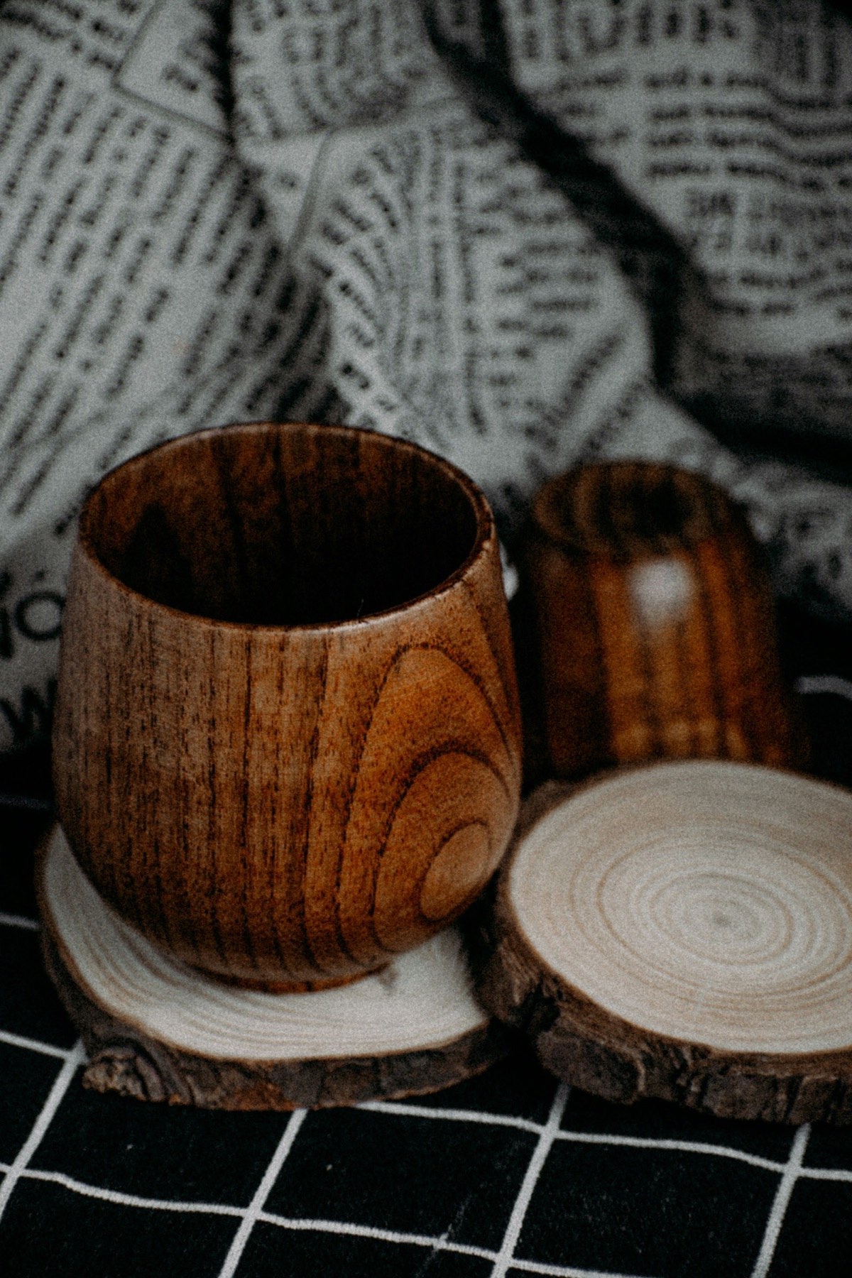 a wooden cup sitting on top of a wooden coaster on a natural surface