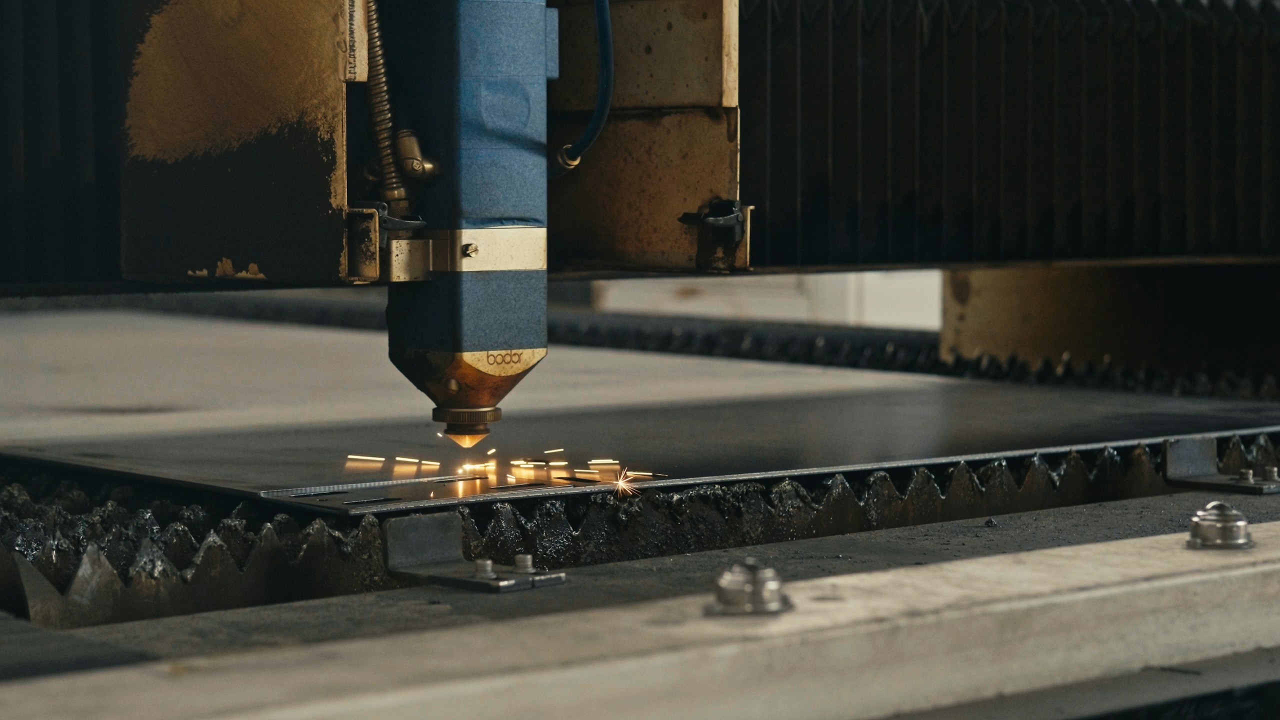 a laser cutting machine precisely cuts through a metal sheet producing bright sparks in a workshop